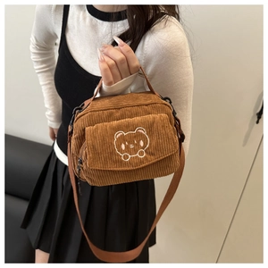 Detail of a brown corduroy crossbody bag featuring a cute cartoon bear embroidery