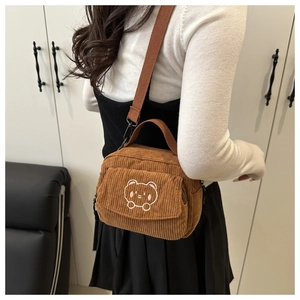 Detailed close-up of brown corduroy crossbody bag featuring cute bear embroidery detail
