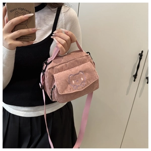 Detailed view of pink corduroy crossbody bag with cute purple bear embroidery and strap