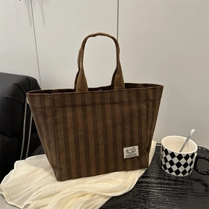 Vintage brown corduroy tote bag with camping label on a minimalist white fabric background