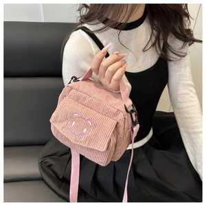 Close-up of pink corduroy crossbody bag with cute purple bear embroidery detail