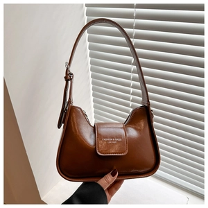 Close-up of brown leather crescent bag showing the logo detail and adjustable shoulder strap