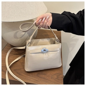 Detail of off-white leather bag with silver twist lock on wooden table and soft lighting