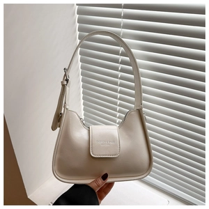 Detail of beige underarm bag with silver metal buckle and adjustable leather strap