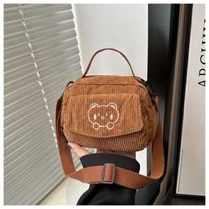 Close-up of brown corduroy messenger bag featuring cute bear embroidery and top handle