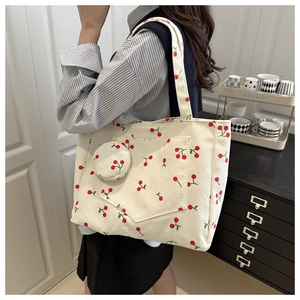 Close-up of beige corduroy tote bag with red cherry prints and matching coin purse