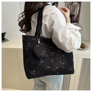 Detail of black corduroy tote bag with red cherry pattern and a matching mini coin purse