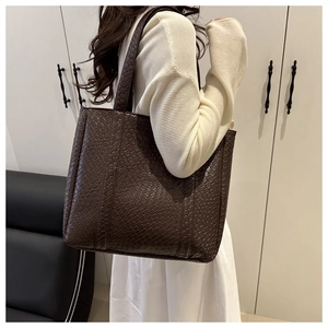 Detailed side view of large dark brown tote bag with premium crocodile pattern texture