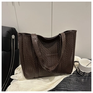 Detail of deep brown woven tote bag texture on a white satin fabric for a chic style