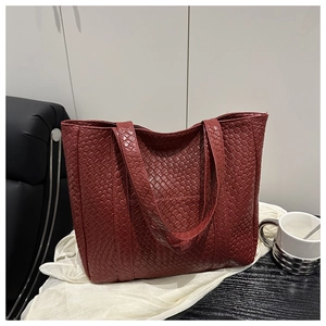 Close-up of burgundy woven tote bag with textured faux leather pattern on silk fabric