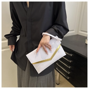 Detail of white envelope clutch with V-shaped gold metal trim and textured leather