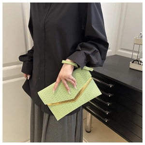 Detail of lime green envelope clutch featuring wavy texture and golden V-shaped metal trim