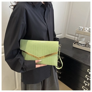 Detail of light green envelope clutch featuring wave texture and golden V-shaped metal trim