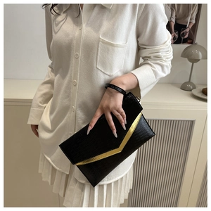 Detail of black wave texture envelope clutch bag with gold metallic V-shaped trim
