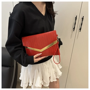 Detail of red envelope clutch featuring wave embossing and golden V-shaped metal trim