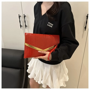 Macro detail of red envelope clutch with water ripple texture and golden V-shaped metal trim