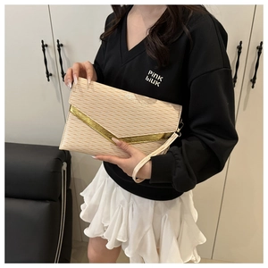 Detail of cream envelope clutch with wavy texture and gold V-shaped metal trim