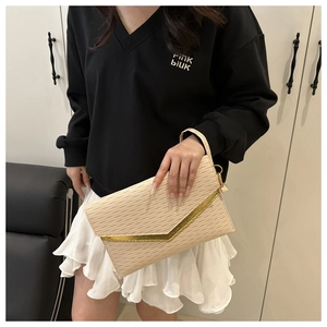 Detail of beige textured envelope clutch featuring a gold V-shaped metal trim and strap