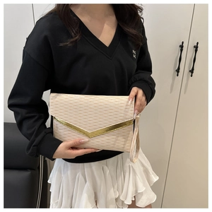 Detail of cream envelope clutch bag with 3D wave texture and gold V-shaped metal trim
