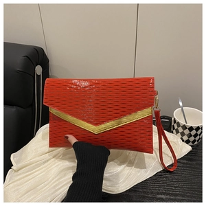 Macro detail of red envelope clutch featuring water wave texture and gold V-shaped metal trim