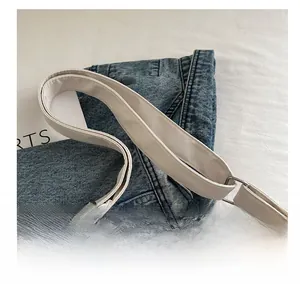 Detail of blue denim fabric crossbody bag with adjustable cream leather shoulder strap