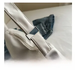 Detail of the white shoulder bag with metal square buckle and wide fabric strap