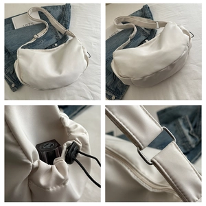 Detail view of a white nylon crossbody tote bag showing adjustable strap and side pocket