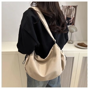 Detail view of a soft beige nylon hobo bag featuring drawstring details and a wide strap