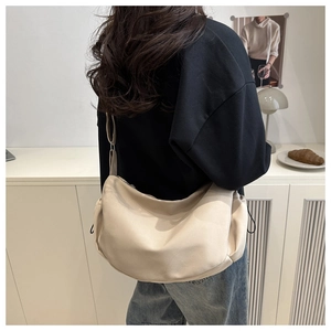 Detail of adjustable strap on a soft beige crescent-shaped nylon crossbody bag