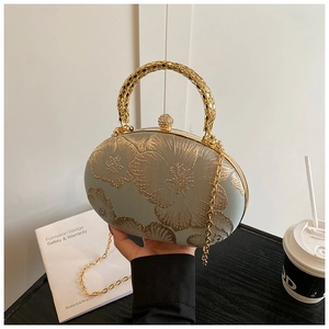 Dettaglio della borsa da sera in raso verde con ricamo floreale e chiusura con strass