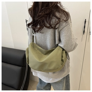 Detailed back view of green nylon dumpling bag worn by model in a home setting