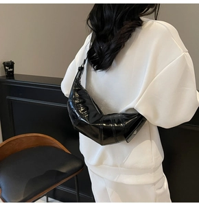 Detail of a black glossy croissant bag showing the quilted texture and pleated finish