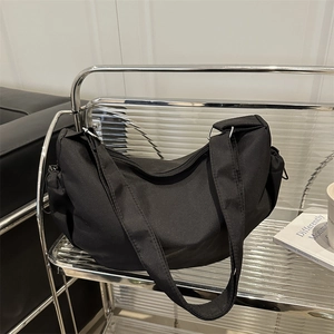 Minimalist black nylon half-moon crossbody bag with wide strap on modern glass shelf
