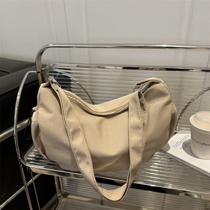 Minimalist beige nylon crescent shoulder bag on a modern shelf display