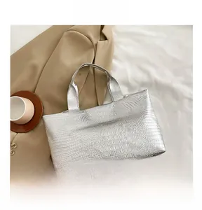 Macro detail of silver crocodile embossed tote bag with smartphone for size reference