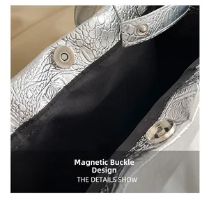 Detail of magnetic closure on silver faux leather tote bag with crocodile texture