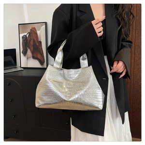 Detail of silver crocodile pattern tote bag with glossy metallic finish and twin handles