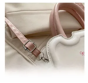 Close-up of adjustable silver buckle and pink strap on white leather handbag detail