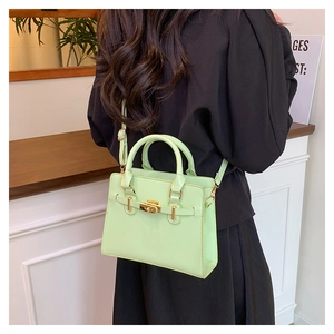 Detail view of mint green trapezoid handbag with gold hardware and shoulder strap