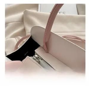 Close-up of smooth silver metal zipper on light pink textured leather crossbody bag