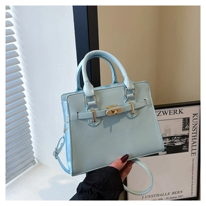 Detailed view of light blue handbag with gold turn-lock closure and leather texture