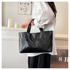 Close-up of glossy black crocodile-embossed faux leather tote bag with elegant texture