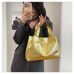 Macro detail of glossy golden tote bag featuring embossed crocodile pattern texture