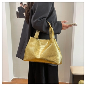 Detailed macro view of large gold tote bag with embossed crocodile skin texture