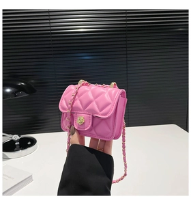 Close-up of pink quilted mini bag with golden camellia lock and chain strap