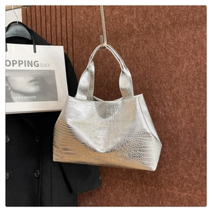 Close-up of metallic silver tote bag with embossed crocodile pattern and wide handle