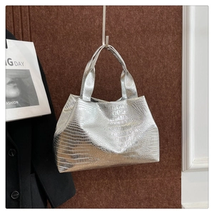 Detail of silver crocodile pattern tote bag showing metallic texture and handles