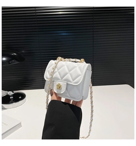 Macro detail of white quilted crossbody bag featuring a golden floral clasp and chain