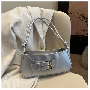 Detail showing metallic silver underarm bag with knot handle and belt buckle decor