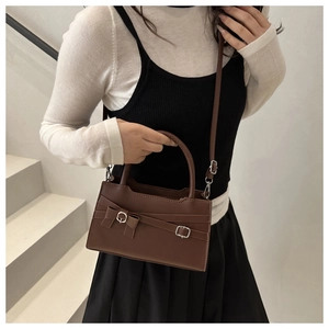 Brown retro square handbag with bow accent and metal buckle detail on a white staircase